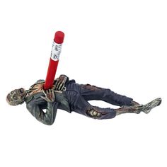 a zombie figurine with a baseball bat in his hand, laying on the ground