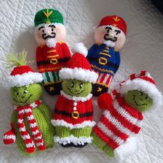 four knitted christmas toys sitting on top of a bed