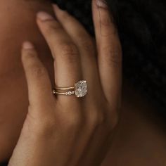 a woman's hand wearing a gold ring with a pear shaped diamond on it