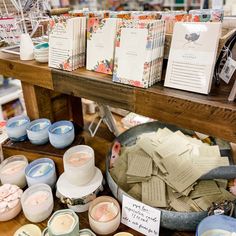 there are many candles and cards on display at the table with it's price tags