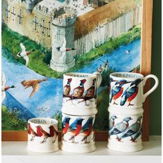 three mugs with birds painted on them next to a painting