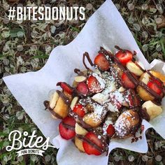 a pastry with strawberries, bananas and chocolate drizzled on top sits in the grass