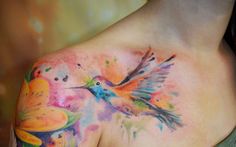 a colorful hummingbird tattoo on the back of a woman's upper arm and shoulder