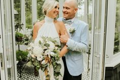 a man and woman standing next to each other in front of a glass wall with flowers