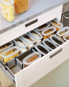 an open drawer in a kitchen filled with lots of containers and trays full of food