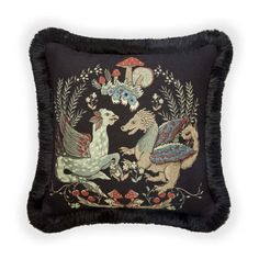 an embroidered pillow with two horses and mushrooms on the front, surrounded by black feathers