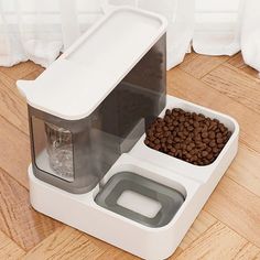 a dog food dispenser on the floor next to a bowl of water