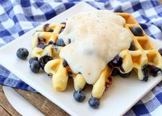 a waffle topped with blueberries and cream on top of a white square plate