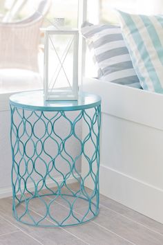 a blue side table with a lamp on top in front of a white window sill