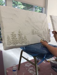 a man is working on a large piece of art that looks like snow covered trees