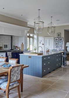 a large kitchen with blue cabinets and an island in the middle is shown, along with two dining chairs