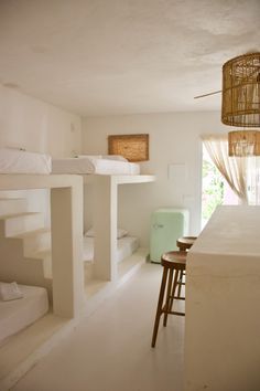 a room with white walls and flooring, including bunk beds in the middle next to each other