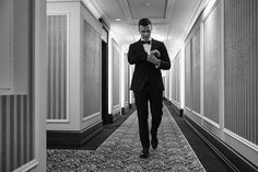 a man in a tuxedo is looking at his cell phone while walking down the hallway