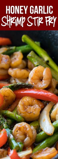 a skillet filled with shrimp, asparagus and carrots in a stir fry