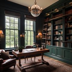 a room with green bookshelves, leather chairs and a wooden table in front of two large windows