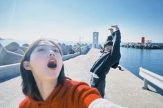 two people standing on a pier with their arms in the air and one person reaching up