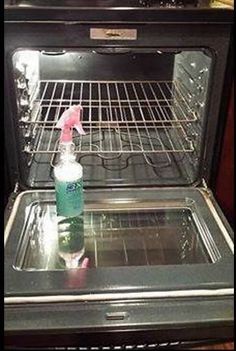 an open oven with a bottle of cleaner on the top and bottom, in front of it