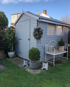 a small gray house with potted plants and a bench in the front yard area