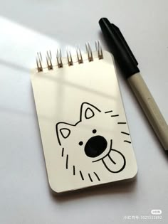 a notepad with a cat drawn on it next to a pen