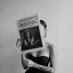 a woman in black dress holding up a newspaper