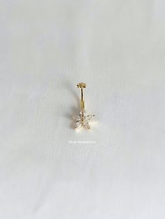 a gold nose ring with two small white flowers on the top and one smaller flower in the middle