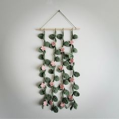 a crocheted wall hanging with pink and green flowers attached to the side of it