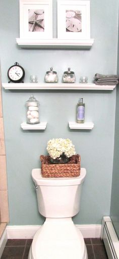 a white toilet sitting in a bathroom next to a shelf filled with pictures and flowers