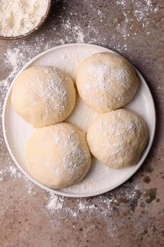 four doughnuts on a plate with powdered sugar