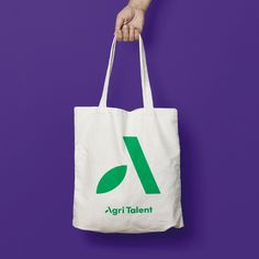 a person holding a white bag with the word agri talent on it, against a purple background