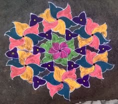 a colorful flower design is painted on the ground with chalk pastel pencils and colored paper