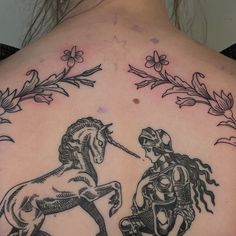 a woman with a tattoo on her back is looking at a horse that appears to be touching it's head