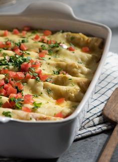 a casserole dish with tomatoes, cheese and herbs