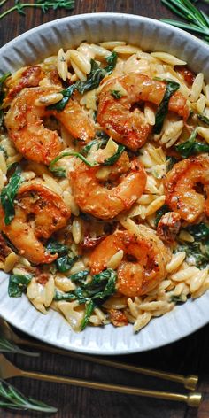 pasta with shrimp, spinach and pine nuts in a white bowl on a wooden table