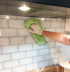 a person with gloves on their arms cleaning a kitchen stove top oven in the process of being cleaned