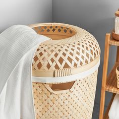 a basket with a white towel on it next to a wooden shelf filled with towels