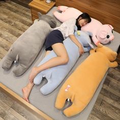 a woman laying on top of a bed with stuffed animals around her and an elephant sleeping next to her