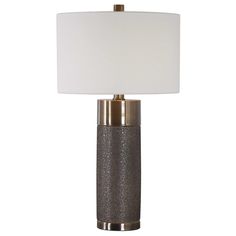 This contemporary table lamp design showcases a heavily textured ceramic base that is finished in a metallic golden bronze, paired with antique brass plated iron details. A hardback drum shade in an off-white linen fabric completes this piece. Uttermost Lamps, Contemporary Table Lamp, Transitional Table Lamps, Bronze Table Lamp, Bronze Table, Contemporary Table Lamps, Contemporary Table, Brass Table, Table Lamp Design