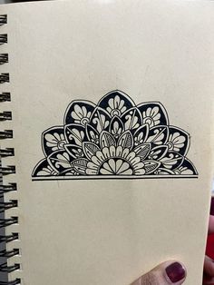 a hand holding a notebook with an intricate design on it