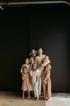 a group of people standing next to each other in front of a black wall with their arms around one another