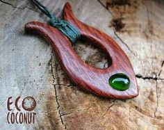 a piece of wood with a green glass bead in it's center on a string