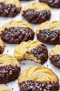 cookies with chocolate frosting and sprinkles are on a baking sheet, ready to be eaten