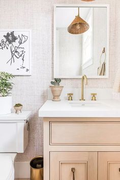 a white toilet sitting under a bathroom mirror next to a wooden sink vanity and potted plant