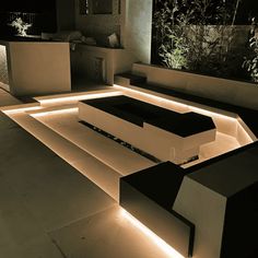 a modern outdoor living room with lighting on the floor and couches in the center