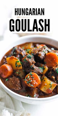 a bowl of hungarian goulash with carrots, potatoes and parsley on the side