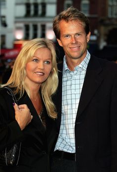 a man and woman standing next to each other on a red carpeted area with buildings in the background