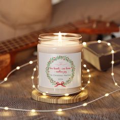 a lit candle sitting on top of a wooden table next to a string of lights