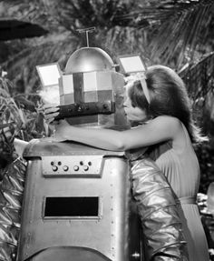 two people hugging each other in front of a robot