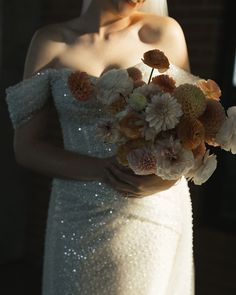 a woman in a wedding dress holding a bouquet of flowers