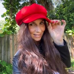 a woman with long brown hair wearing a red hat and black jacket, posing for the camera