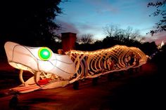 a large white boat with green eyes on it's side at night, lit up by string lights